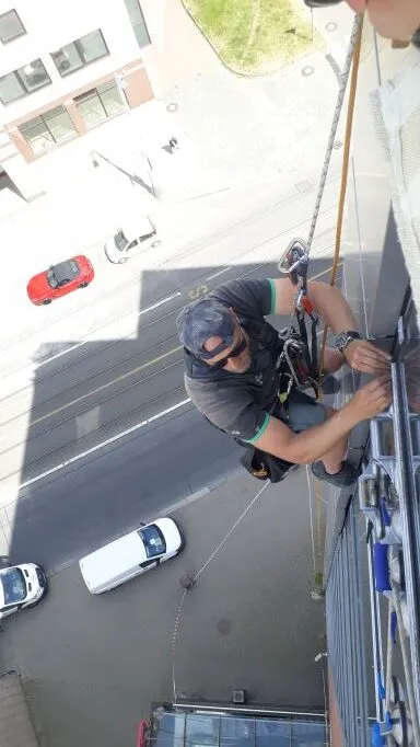 Výškový pracovník při zásahu na fasádě činžovního domu